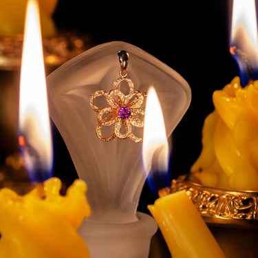 0.18ct natural alexandrite flower pendant in 18k rose and white multitone gold with diamond accents displayed with candlelight